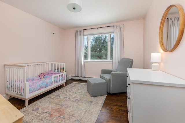 bedroom featuring a baseboard radiator, a nursery area, and dark wood-style flooring