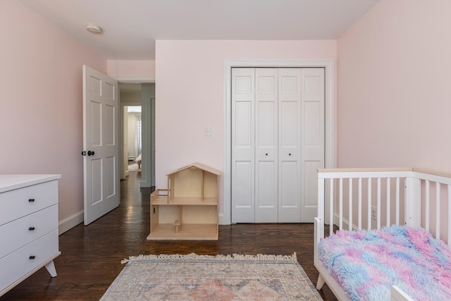 bedroom featuring dark wood-type flooring, baseboards, and a closet