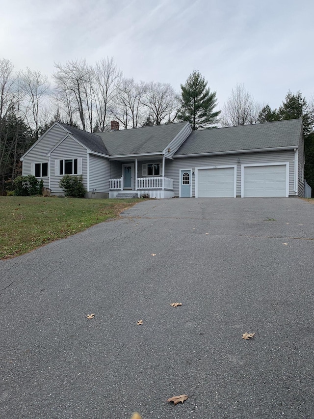 ranch-style house featuring an attached garage, covered porch, a chimney, a front lawn, and aphalt driveway