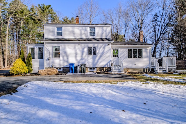 snow covered rear of property featuring a chimney