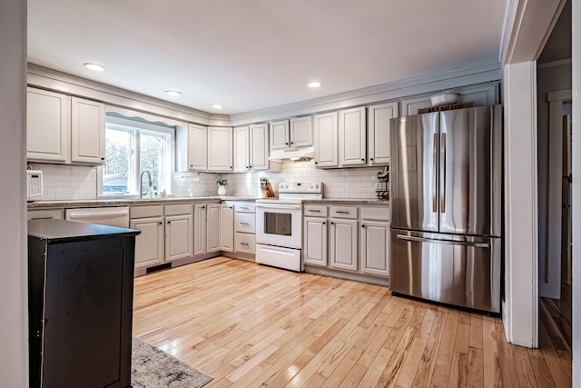 kitchen with under cabinet range hood, backsplash, white appliances, and light wood-type flooring