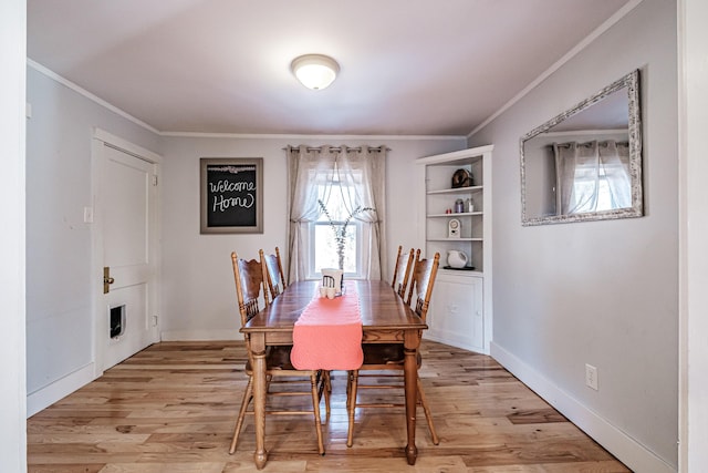 dining space with baseboards, ornamental molding, and light wood finished floors