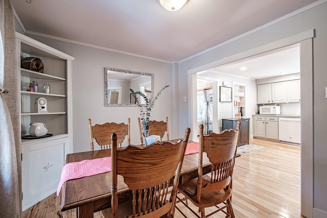 dining space with light wood-style flooring and ornamental molding