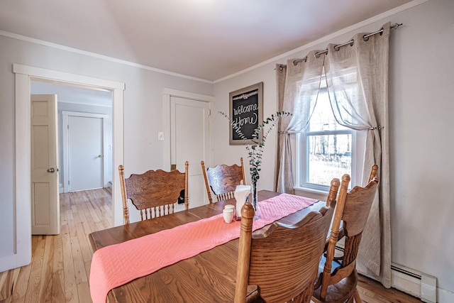 dining room featuring baseboard heating, light wood-type flooring, and crown molding