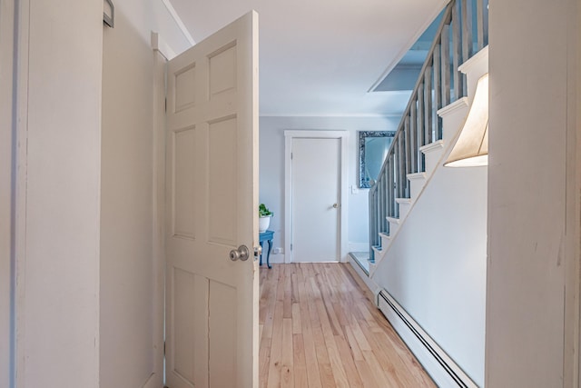 entryway with light wood-style floors, baseboard heating, and stairway