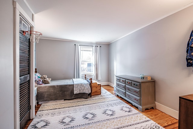 bedroom with crown molding, light wood-type flooring, and baseboards