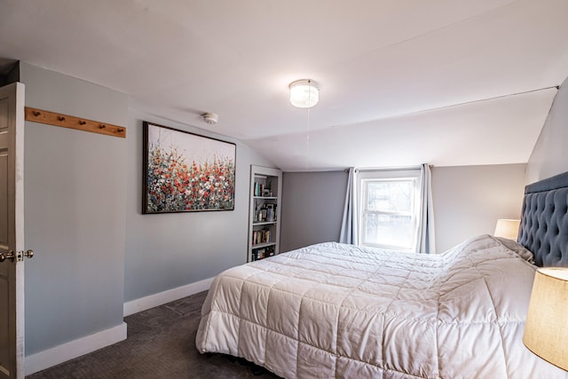 bedroom with dark carpet, lofted ceiling, and baseboards