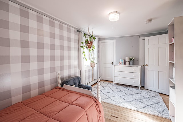 bedroom featuring wallpapered walls, wood finished floors, and a baseboard radiator