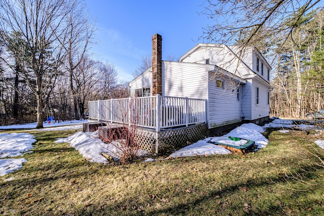 view of side of home with a deck, a lawn, and a chimney