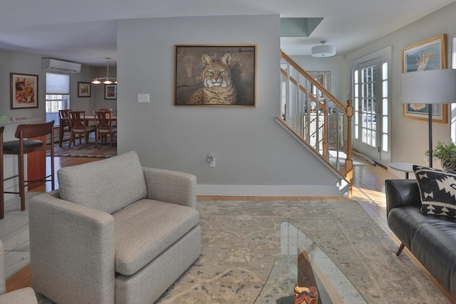 living room featuring baseboards, stairs, a wall mounted AC, and wood finished floors