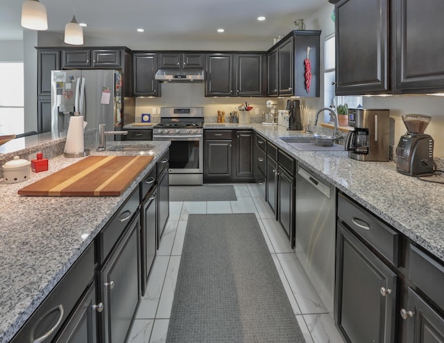 kitchen with under cabinet range hood, stainless steel appliances, a sink, and light stone counters