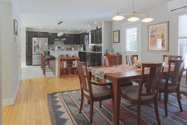 dining space with light wood-style floors, a wall mounted air conditioner, and recessed lighting