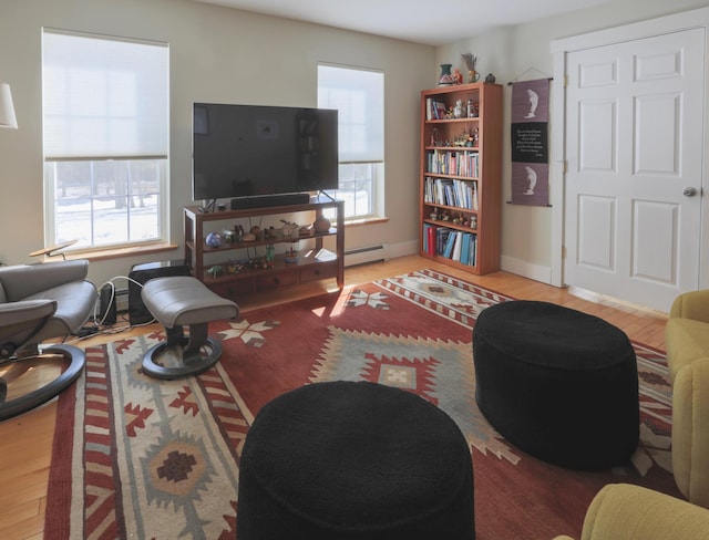 living room with a baseboard heating unit, baseboards, and wood finished floors