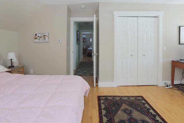 bedroom featuring lofted ceiling, wood-type flooring, and a closet