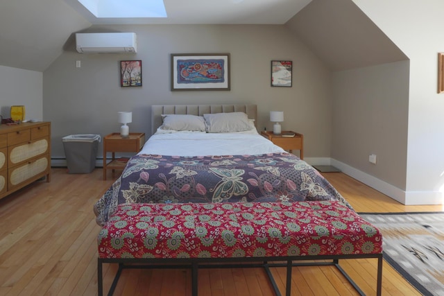 bedroom featuring a wall mounted air conditioner, vaulted ceiling with skylight, baseboards, baseboard heating, and hardwood / wood-style flooring