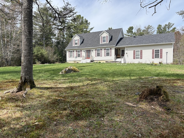 cape cod-style house featuring a front yard, roof with shingles, and entry steps