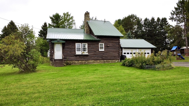 view of side of property with a lawn, a playground, metal roof, a garage, and a chimney