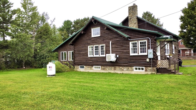 rear view of property with log exterior, a chimney, and a yard