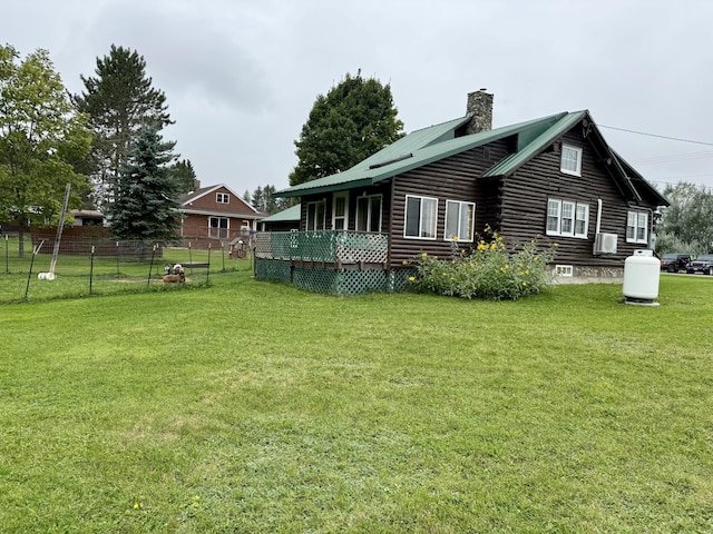 back of property featuring metal roof, a lawn, a chimney, and fence