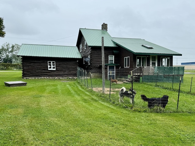 exterior space with a yard, metal roof, log exterior, and a chimney