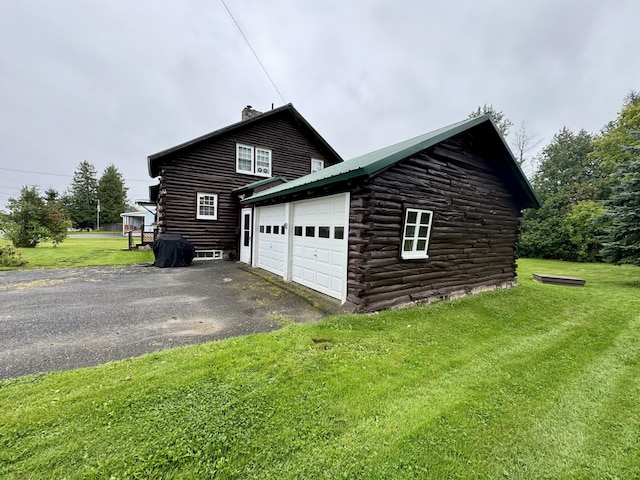 view of home's exterior with log siding, a lawn, metal roof, and aphalt driveway