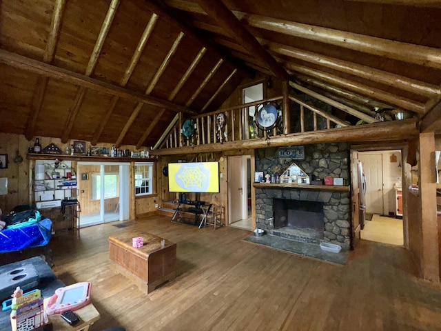 living room featuring a stone fireplace, high vaulted ceiling, and wood finished floors