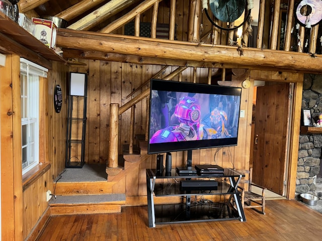 cinema room featuring vaulted ceiling, wooden walls, and hardwood / wood-style floors