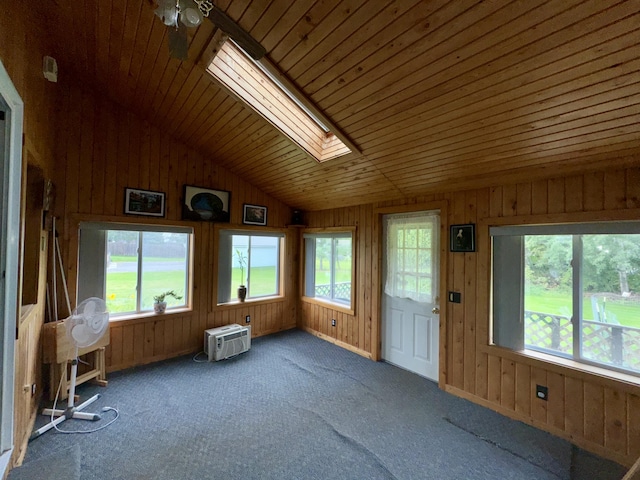 unfurnished sunroom featuring lofted ceiling with skylight, an AC wall unit, and a healthy amount of sunlight