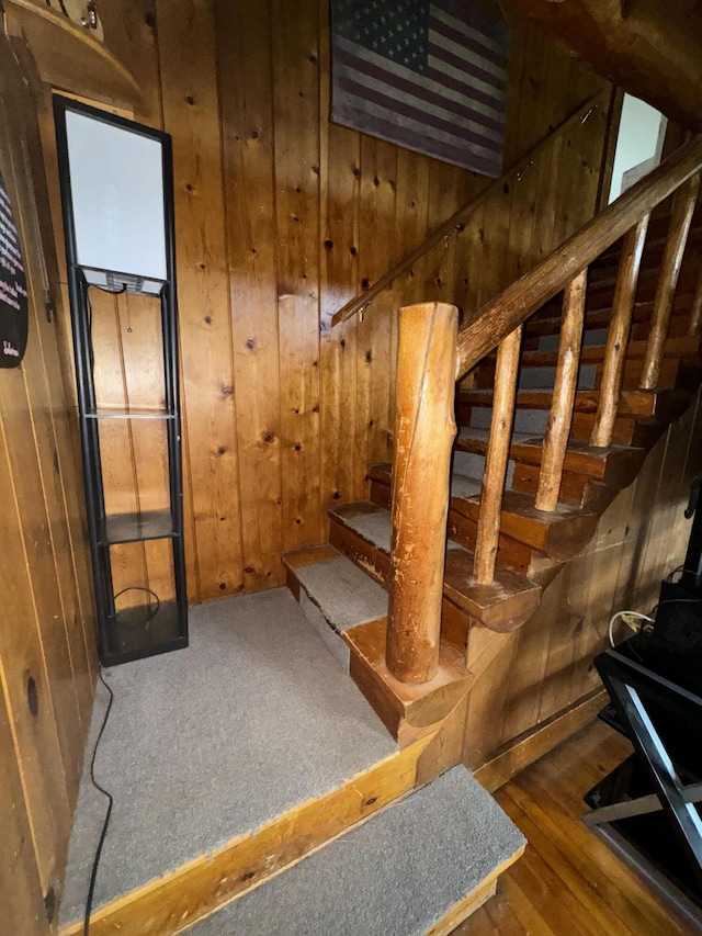 staircase with wooden walls and wood finished floors