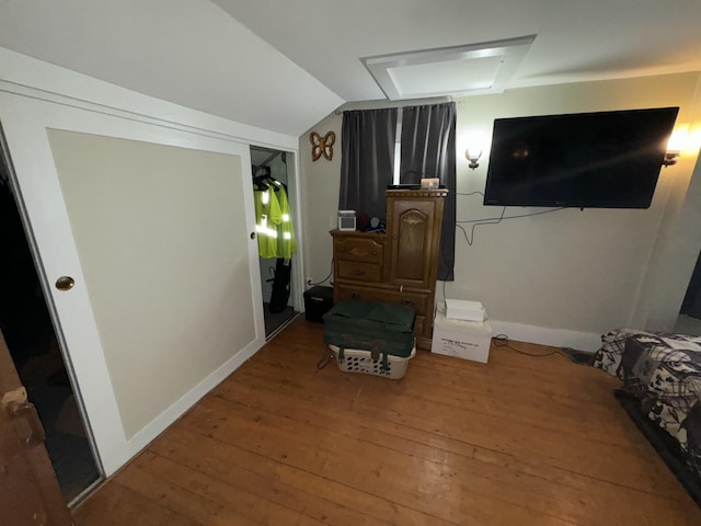 interior space with lofted ceiling, attic access, baseboards, and wood-type flooring