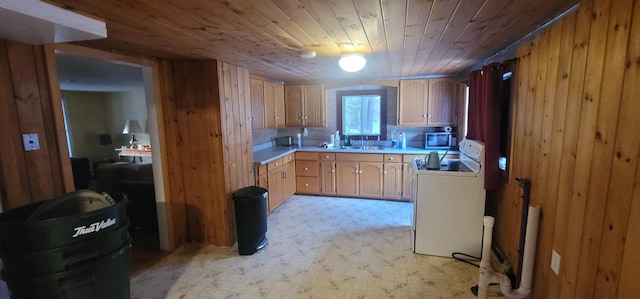 kitchen featuring stainless steel microwave, white range with electric stovetop, wooden walls, light countertops, and light floors