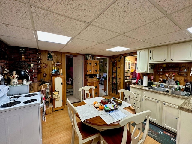 kitchen with white electric range, a sink, light wood finished floors, a paneled ceiling, and light countertops