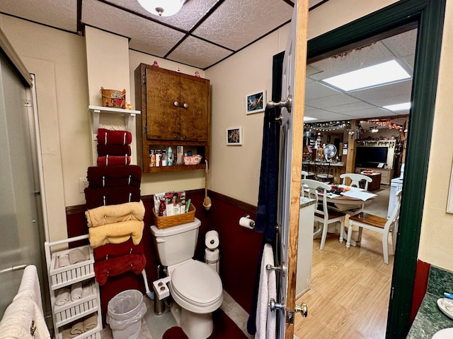 bathroom featuring a drop ceiling, toilet, and wood finished floors