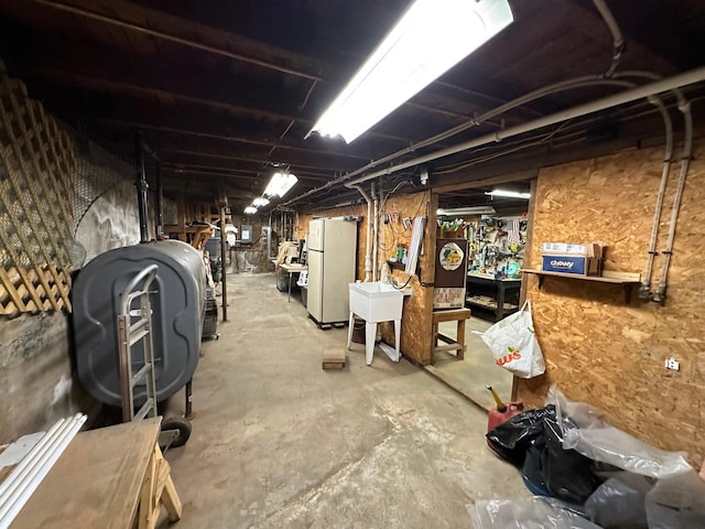 unfinished basement with heating fuel and freestanding refrigerator