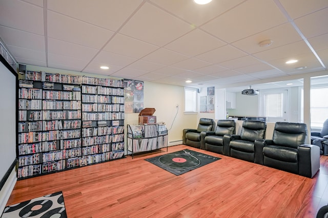 home theater featuring baseboard heating, recessed lighting, a paneled ceiling, and wood finished floors