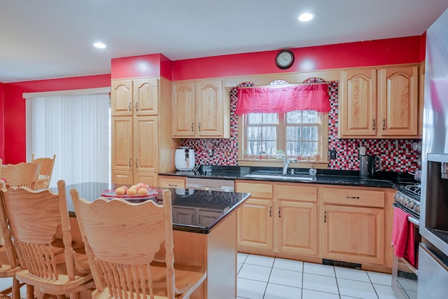 kitchen featuring stainless steel gas stove, light brown cabinets, a sink, tasteful backsplash, and light tile patterned floors