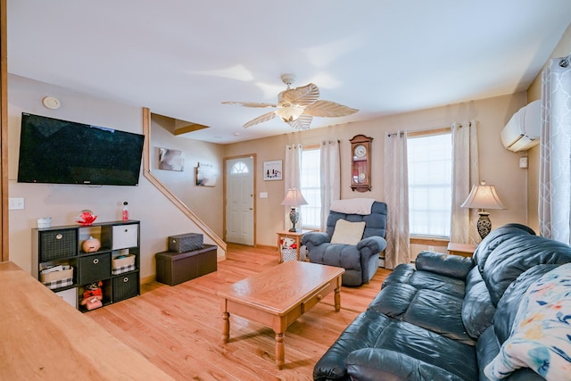 living room with a wall mounted air conditioner, wood finished floors, and ceiling fan