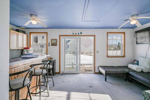 interior space featuring attic access, a ceiling fan, and concrete floors