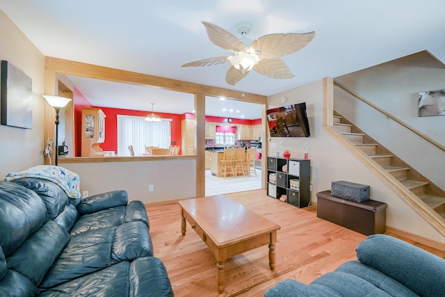 living area with stairs, a ceiling fan, and wood finished floors