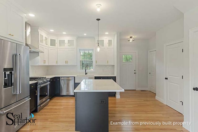 11 Clam Ln Unit A, Wells, ME 04090 - kitchen with high end appliances, wall chimney exhaust hood, a sink, white cabinets, and light wood finished floors