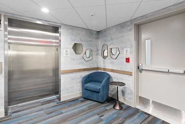 interior space featuring elevator, a paneled ceiling, and carpet floors