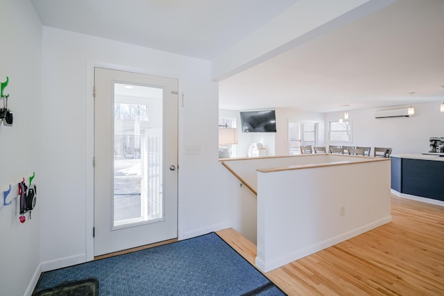 entryway featuring light wood-style flooring, an AC wall unit, and baseboards