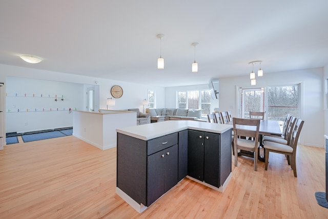 kitchen featuring hanging light fixtures, open floor plan, a center island, and light wood-style floors