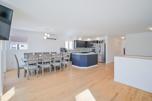 dining area with light wood-style flooring, a wall mounted AC, and baseboards