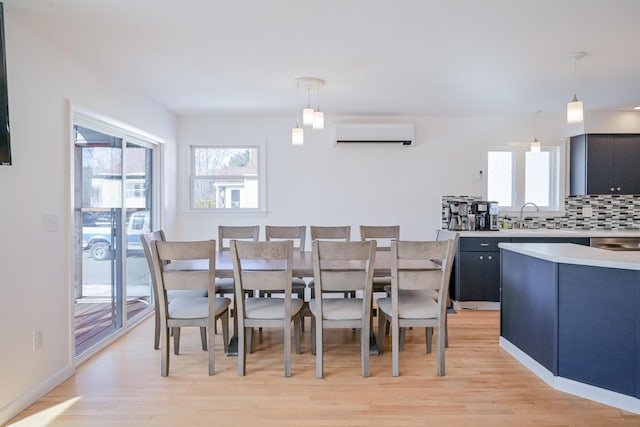 dining area featuring a healthy amount of sunlight, baseboards, light wood-style floors, and a wall unit AC