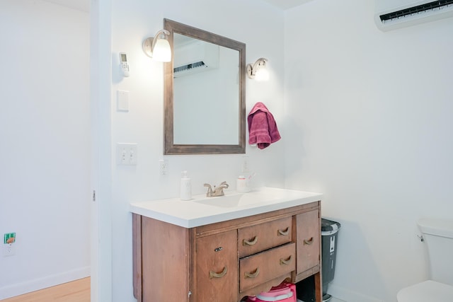 half bathroom with baseboards, toilet, an AC wall unit, and vanity