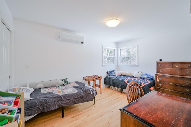 bedroom featuring an AC wall unit, wood finished floors, and a closet