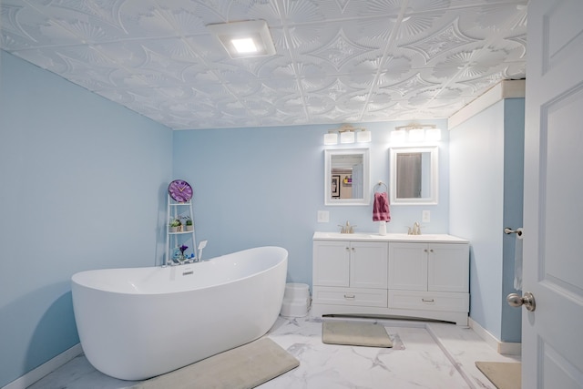 full bath featuring baseboards, a freestanding bath, double vanity, marble finish floor, and a sink