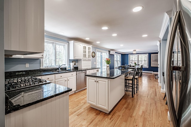 kitchen featuring ornamental molding, a kitchen breakfast bar, a center island, white cabinetry, and stainless steel appliances