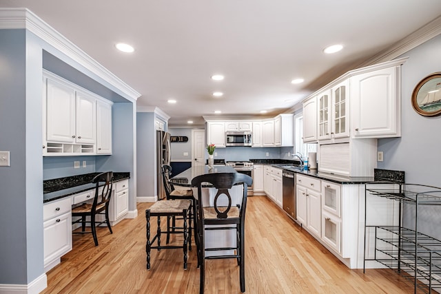 kitchen with built in study area, white cabinets, a breakfast bar, and stainless steel appliances